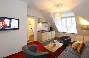 Aparthotel Markt Fuffzehn في شترالزوند: غرفة معيشة مع أريكة وكراسي ومطبخ