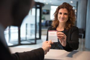 Una mujer entregándole a un hombre un pedazo de papel. en Mercure Roma Piazza Bologna, en Roma