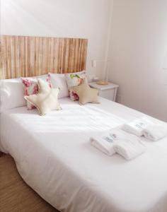 białe łóżko z poduszkami i ręcznikami w obiekcie Casa apartamento a pie de playa Areabrava - en Cangas - Hio -Galicia- España w mieście Hio