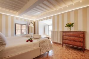 a bedroom with a bed and a dresser and a mirror at Palazzo Chigi Zondadari in Siena