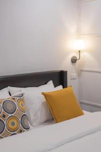 a bed with white and yellow pillows and a lamp at The Mellow Pillow Hotel @ Chiang Mai Gate in Chiang Mai