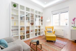 een woonkamer met een gele stoel en boekenplanken bij Luxury Apartment Princesa in Madrid