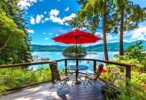 a deck with a table and chairs and an umbrella at Tranquility Bay Waterfront Inn in Sechelt