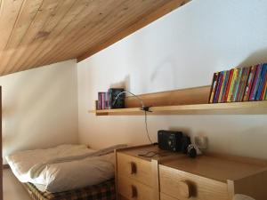 a bedroom with a bed and a desk with books at I dr Rehwiesa C31 in Arosa