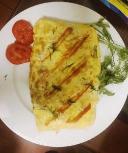 a white plate with a omelet and tomatoes on it at Haengbok Hotel in Bắc Ninh