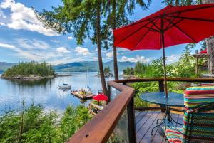 a deck with a table and an umbrella at Tranquility Bay Waterfront Inn in Sechelt