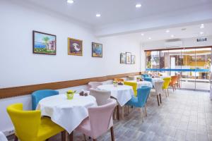 une salle à manger avec des tables blanches et des chaises colorées dans l'établissement Infinity City Hotel, à Fethiye