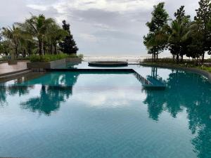 a swimming pool with blue water and palm trees at Sofia Seaview Suite Timurbay Kuantan in Kuantan
