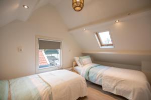 two beds in a room with a window at Vakantiewoning t Uusje Wemeldinge in Wemeldinge