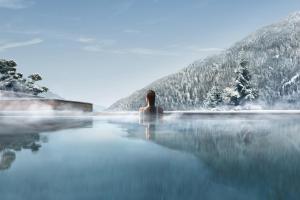 a person sitting in a infinity pool in the mountains at Lefay Resort & SPA Dolomiti in Pinzolo