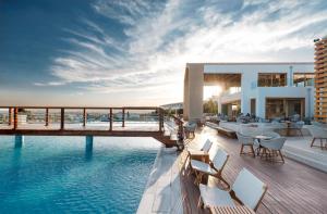 a resort deck with a pool and tables and chairs at Mitsis Selection Blue Domes in Kardamaina