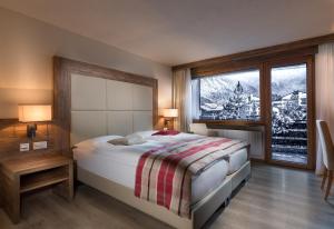 a bedroom with a bed and a large window at Hotel Ambassador Zermatt in Zermatt