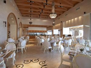 a dining room with tables and white chairs at Mitsis Selection Blue Domes in Kardamaina