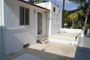 une maison blanche avec une terrasse couverte et une chaise dans l'établissement Cornerbunker, à Mysore