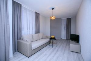 - un salon avec un canapé et une télévision dans l'établissement ГеВе Апартаменти, à Sandanski