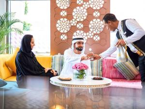 a man serving a meal to a woman at Mercure Hotel Apartments Dubai Barsha Heights in Dubai