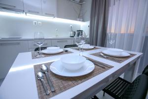 a kitchen with a table with plates and wine glasses at ГеВе Апартаменти in Sandanski