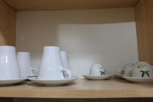 un gruppo di tazze e ciotole bianche su uno scaffale di Residence Sol Levante a Frascati