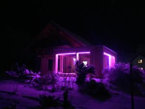 dom z fioletowymi światłami w nocy w obiekcie Alpin Haus Turrach w mieście Turracher Hohe