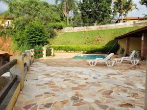 a patio with two chairs and a swimming pool at Pousada Vila Serrana in Serra Negra
