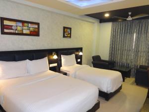 a hotel room with two beds and a chair at Pride Ananya Resorts in Puri