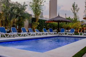 a pool with lounge chairs and an umbrella at Hotel Los Alpes Cipreses in Asunción +26 photos