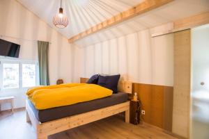 um quarto com uma cama com um cobertor amarelo em BnB Logis des Saules em Saint-Ursanne