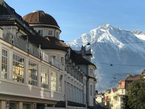 un edificio con una montaña cubierta de nieve en el fondo en Ladurner Suites, en Merano