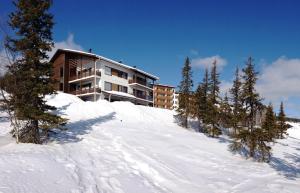 un edificio en la cima de una colina nevada con árboles en Villa Ylläs 101, en Ylläsjärvi