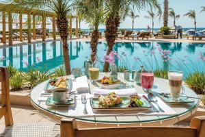 a table with plates of food next to a swimming pool at Mitsis Alila Resort & Spa in Faliraki