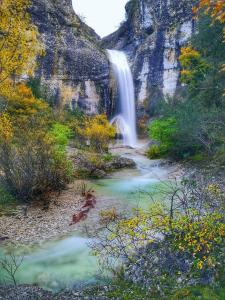 a waterfall on the side of a mountain next to a river at Suite Nid d'Amour et Spa privatif in Vogüé