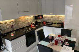 a kitchen with white cabinets and a table with wine glasses at Stefano Rho Apartment Near RHO-FIERA and MILANO in Rho
