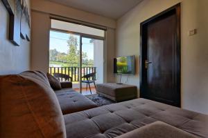 sala de estar con sofá y puerta corredera de cristal en Vista Apartment Mariners Cabin en Nuwara Eliya