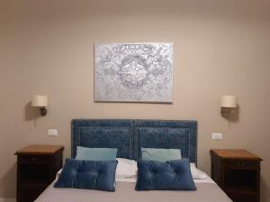 uma cama com almofadas azuis e um quadro na parede em Luxury & Charme Colosseo em Roma