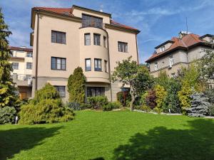 un grand bâtiment avec une pelouse devant lui dans l'établissement Apartment Hanspaulka Garden, à Prague
