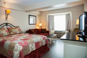 a hotel room with a bed and a flat screen tv at The Village Inn of Lakefield in Lakefield