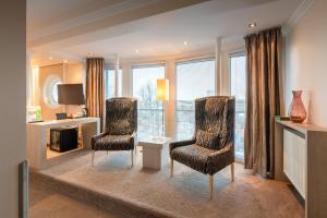 a living room with two chairs and a desk and windows at Thomas Hotel Spa & Lifestyle in Husum