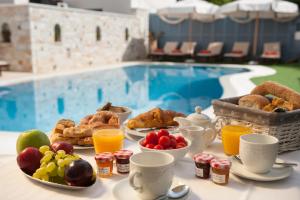 una mesa con desayuno y bebidas junto a una piscina en Anna Platanou Hotel, en Parikia