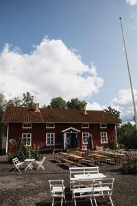 un granero rojo con bancos blancos delante de él en Våffelcafé Bed & Breakfast, en Dannäs
