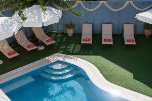 een zwembad met stoelen en een parasol bij Anna Platanou Hotel in Parikia