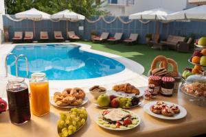 a table with plates of food next to a swimming pool at Anna Platanou Hotel in Parikia