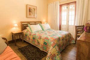 a bedroom with a bed with a colorful comforter at Pousada Encanto da Serra in Tiradentes