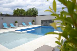 uma piscina com cadeiras azuis num edifício em Hotel Río em Chajarí