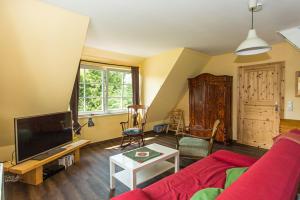 a living room with a red couch and a tv at Hügelhus in Kloster