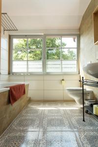 a bathroom with a tub and a sink and two windows at Hügelhus in Kloster