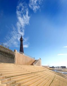 a lighthouse on the beach with a wall and stairs at Cliffs Hotel in Blackpool