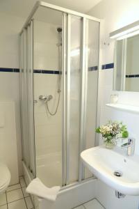 ein Bad mit einer Dusche und einem Waschbecken in der Unterkunft Smart Hostel by Landgasthof Velber 24h7d in Hannover