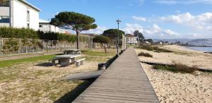eine hölzerne Promenade, die zu einem Strand mit Bänken führt in der Unterkunft APARTAMENTO LUMINOSO EN CANGAS - A in Cangas