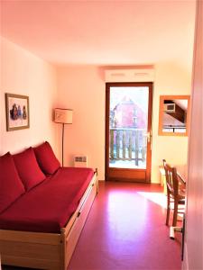 a living room with a red couch and a window at Les Chalets d'Aurouze, La joue du loup in Le Dévoluy