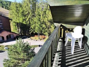 a white chair sitting on a wooden railing on a porch at Les Chalets d'Aurouze, La joue du loup in Le Dévoluy